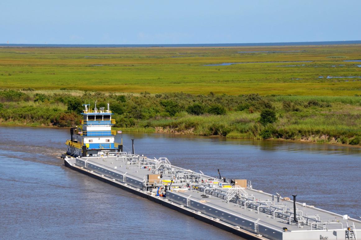 barge traveling through channel surrounded by marsh