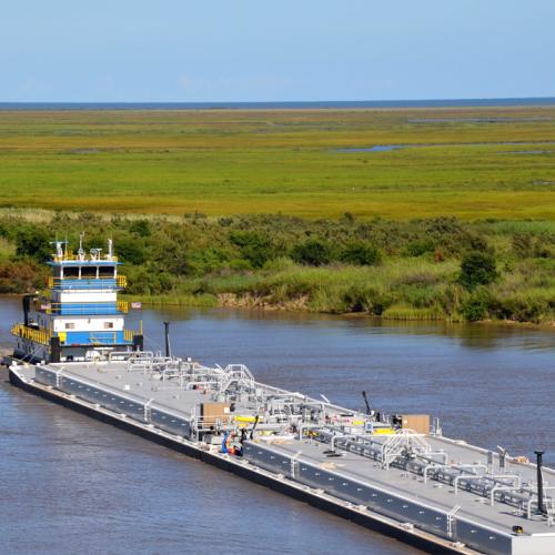 barge traveling through channel surrounded by marsh